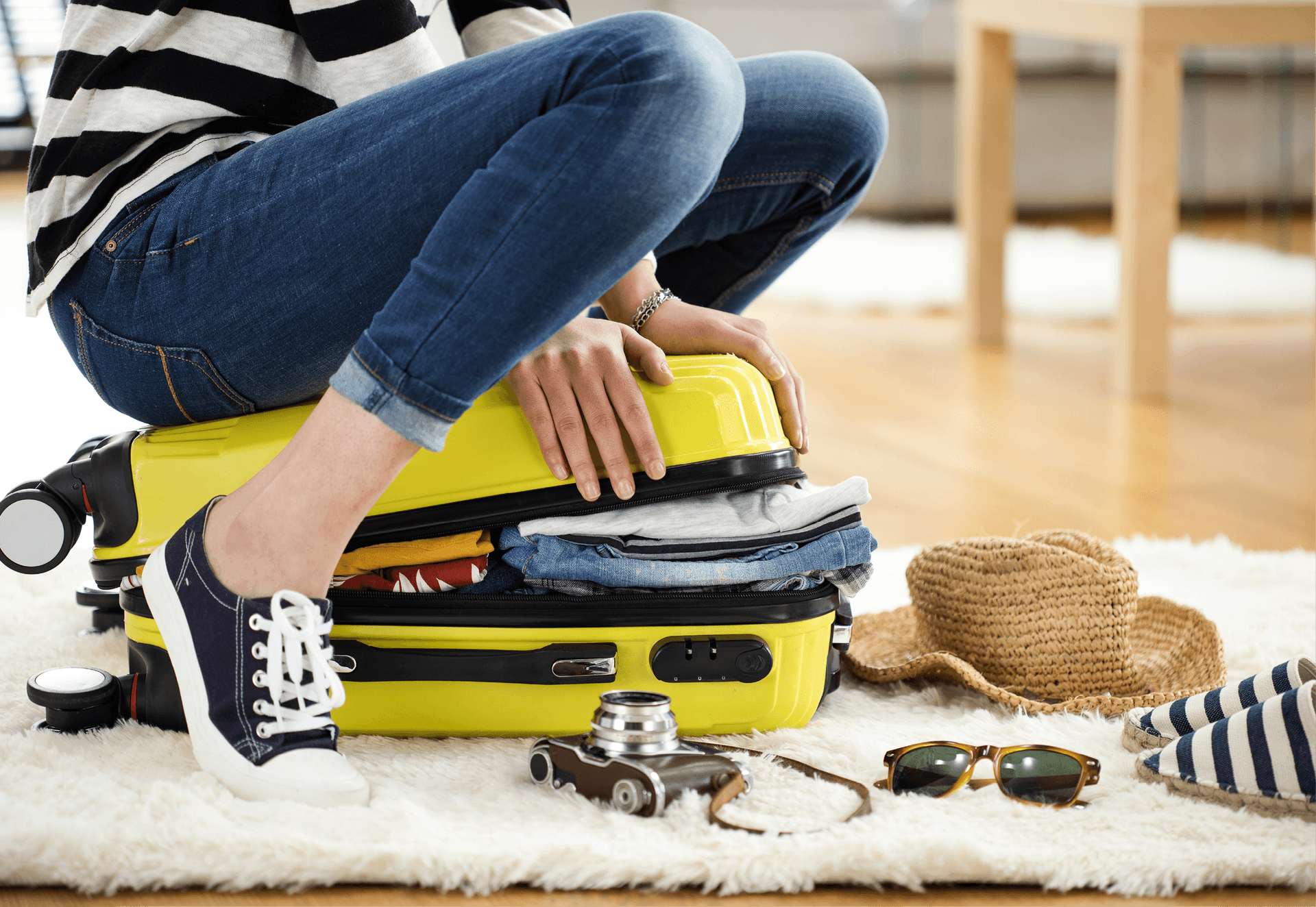 woman sat on suitcase trying to close it