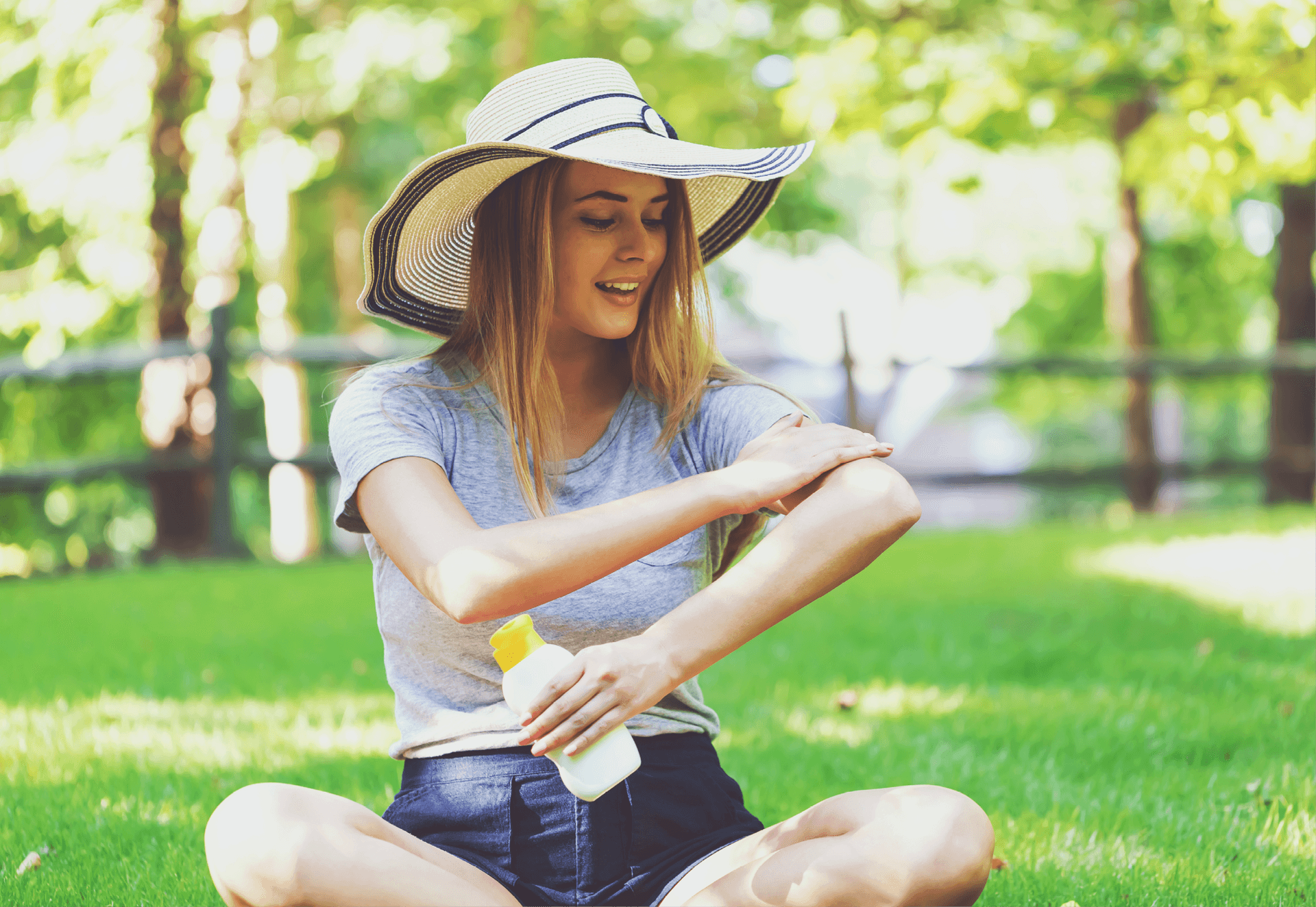 Lady in hat applying suncream to arm