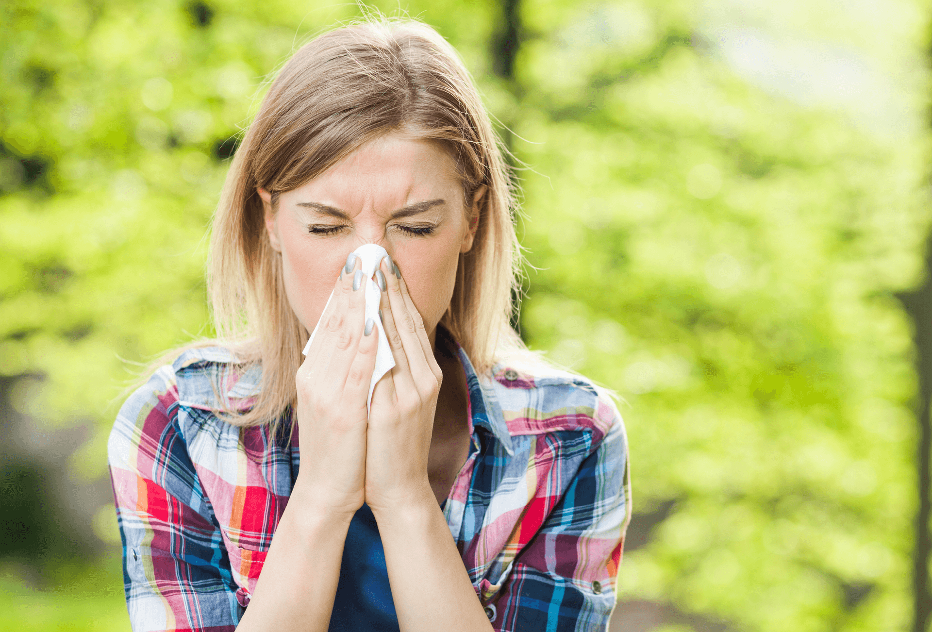 lady blowing nose in a background of grass