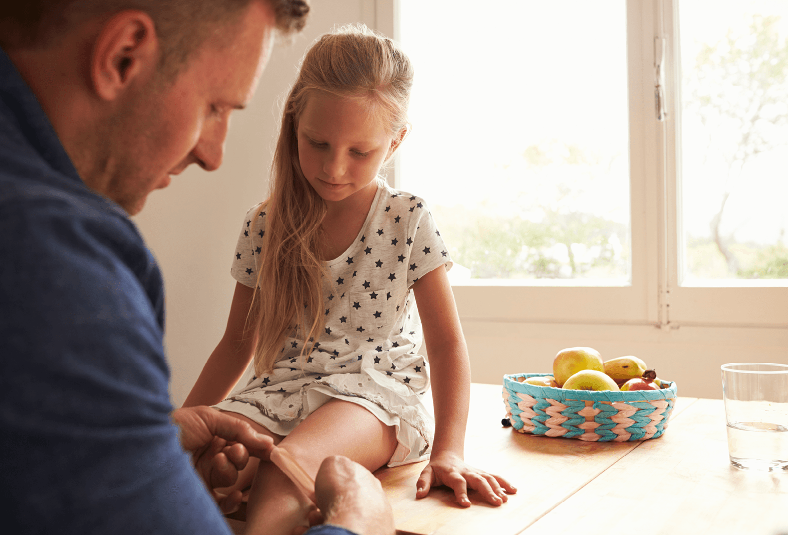 father helping daughter with grazed knee plaster