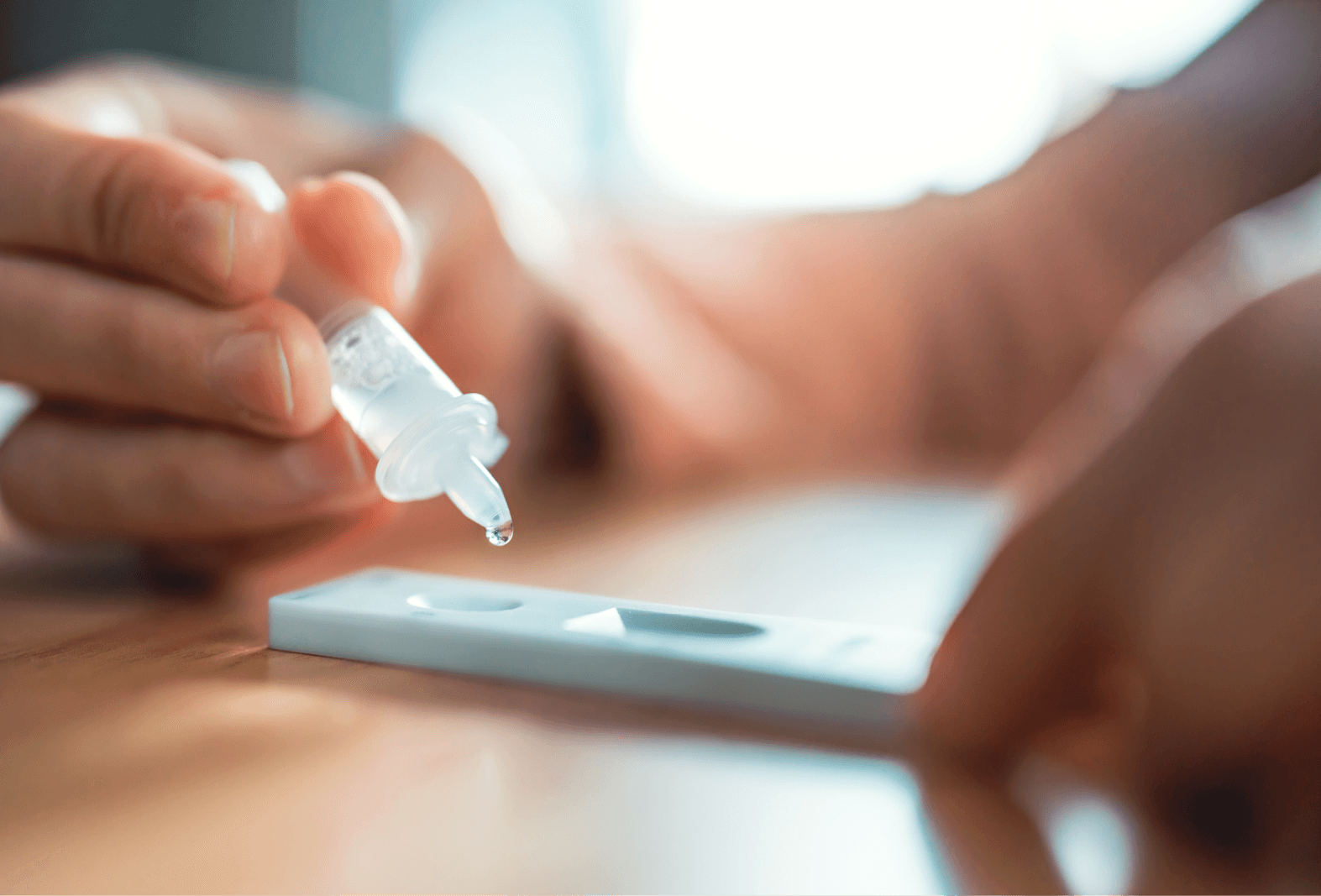 person using a pipette to drop fluid onto the test