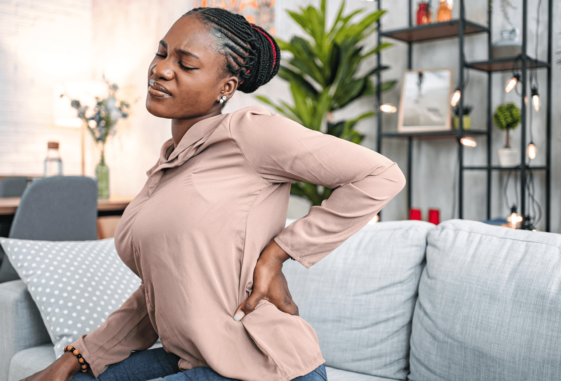 lady sitting and holding lower back in pain