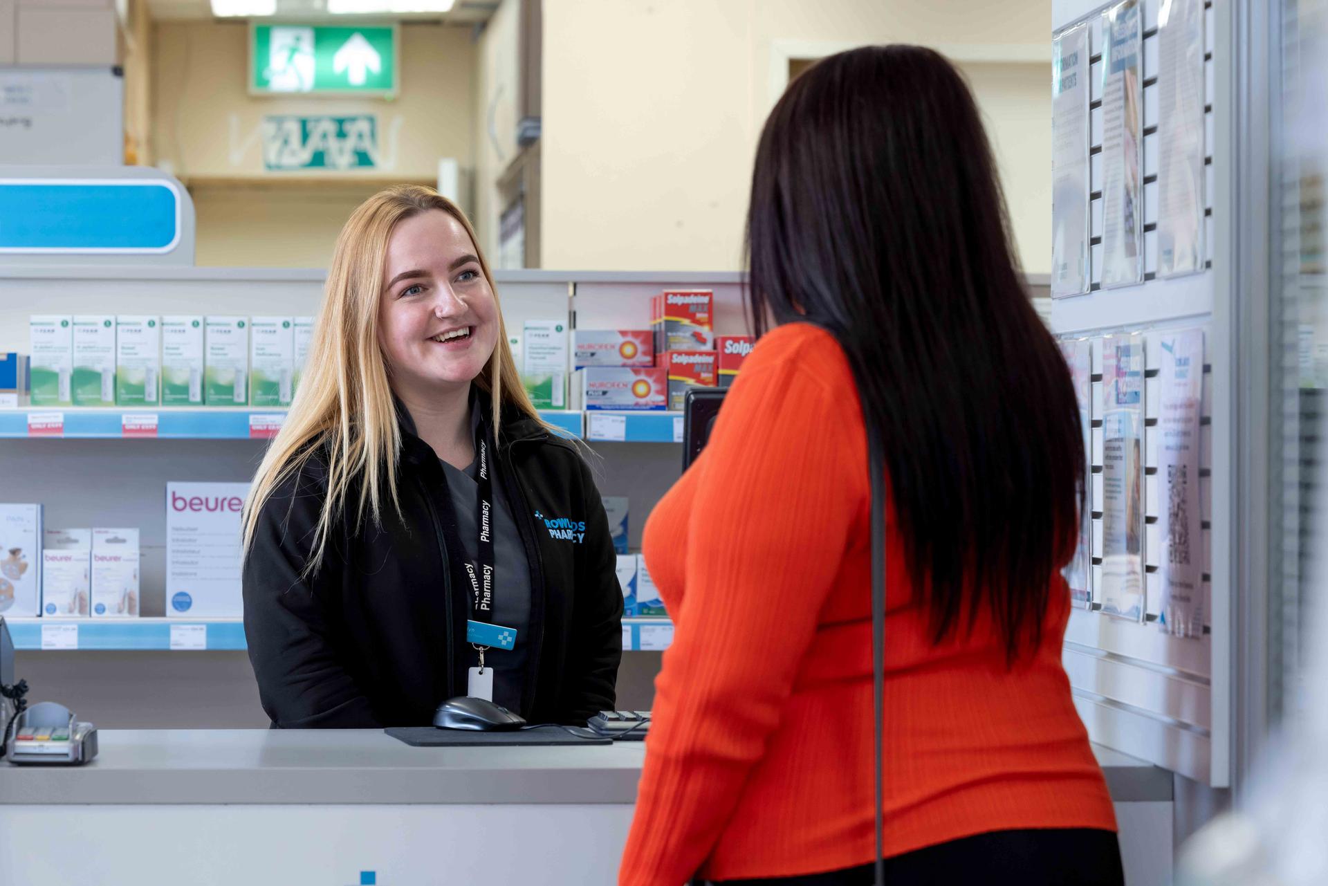 Young female pharmacist speaking to a female customer over the counter