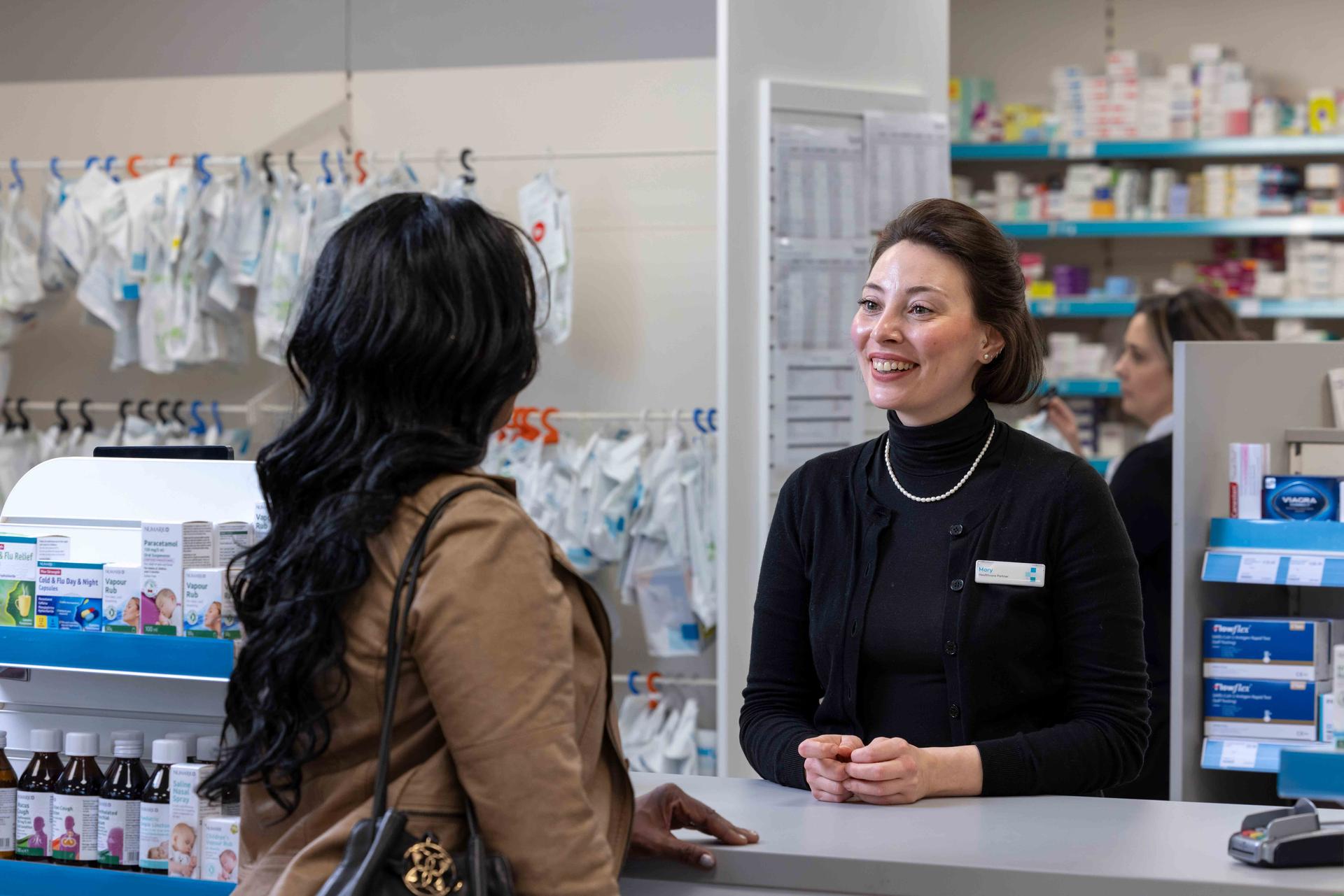 Female pharmacist speaking to a female customer over the counter