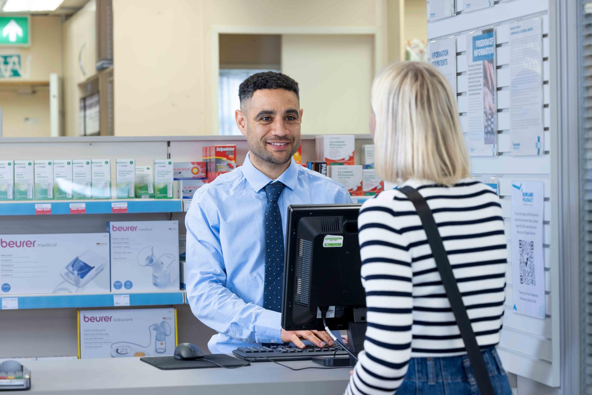 Male pharmacist speaking to a female customer over the counter