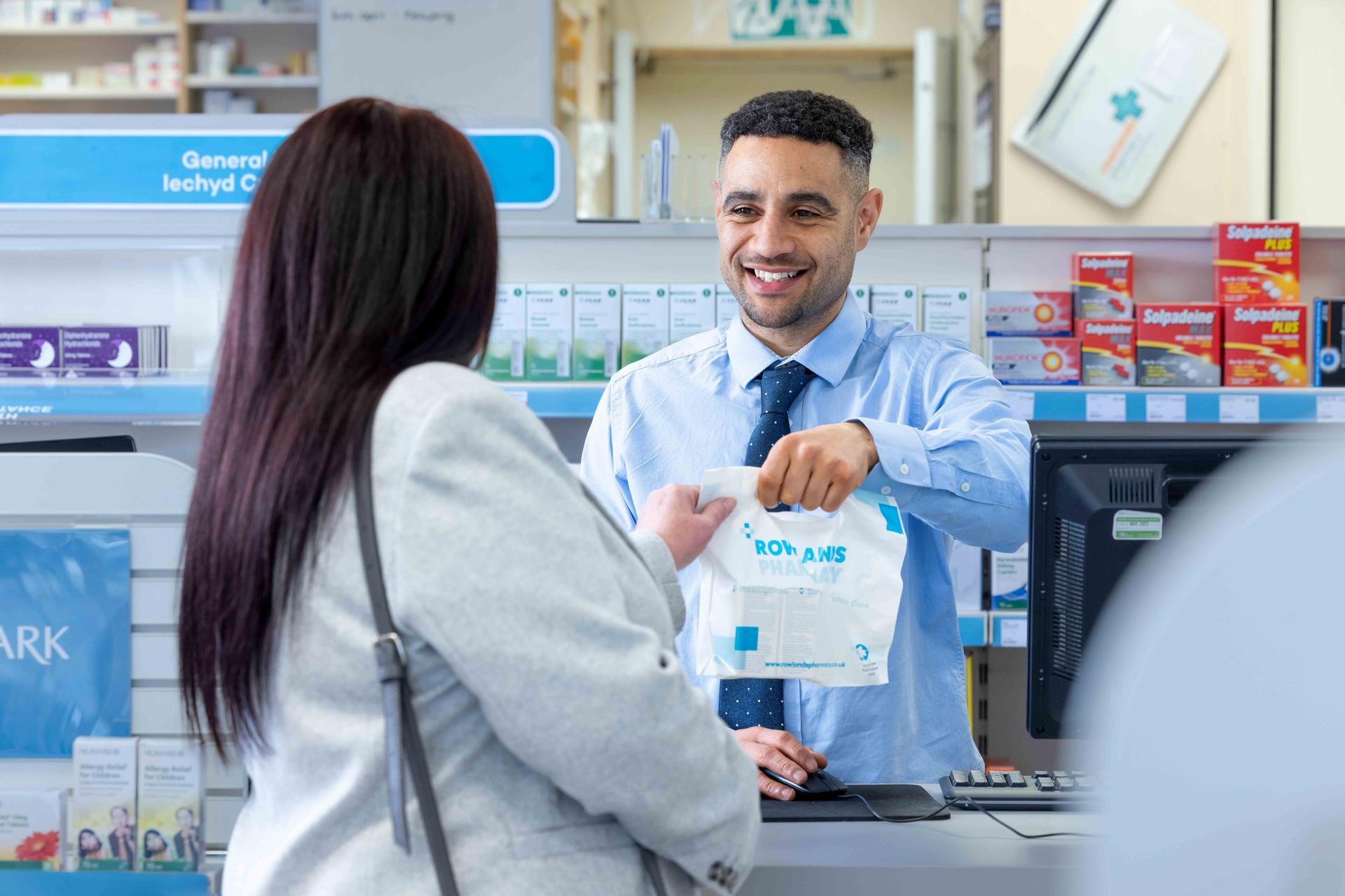Male pharmacist handing over prescriptions to a female patient