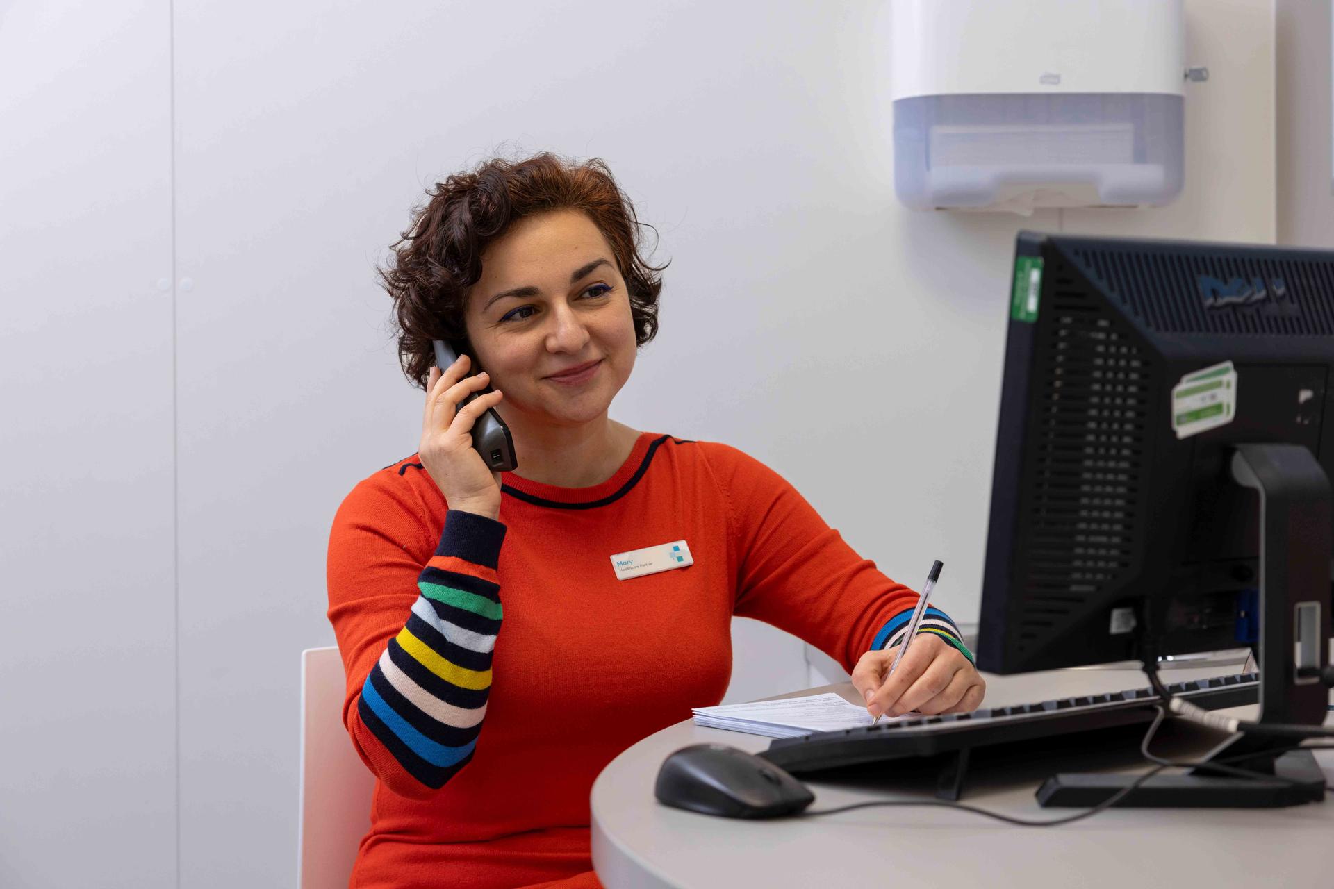 Female pharmacist on the phone whilst using the computer