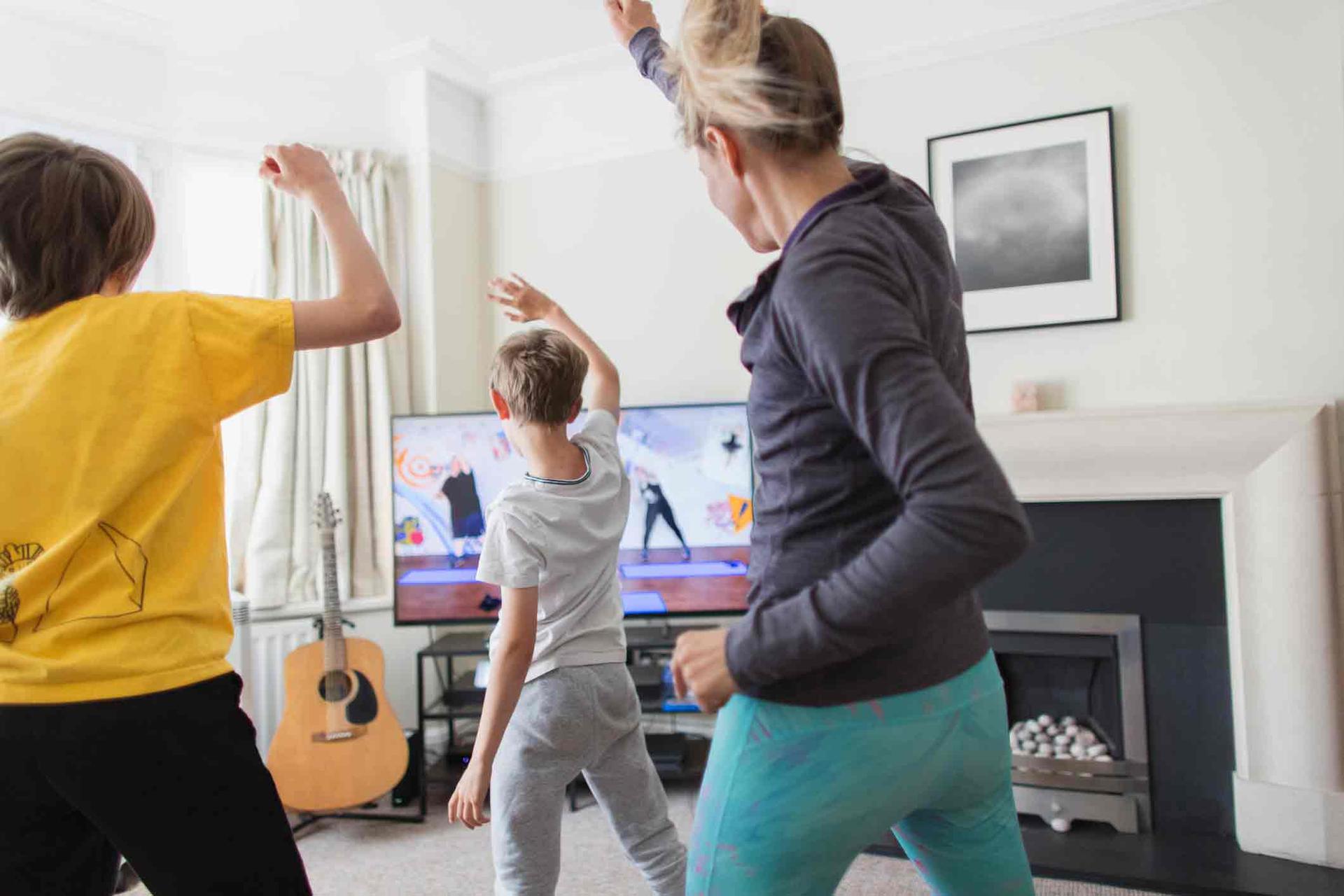 A mother and two sons doing a dance routine in front of the TV