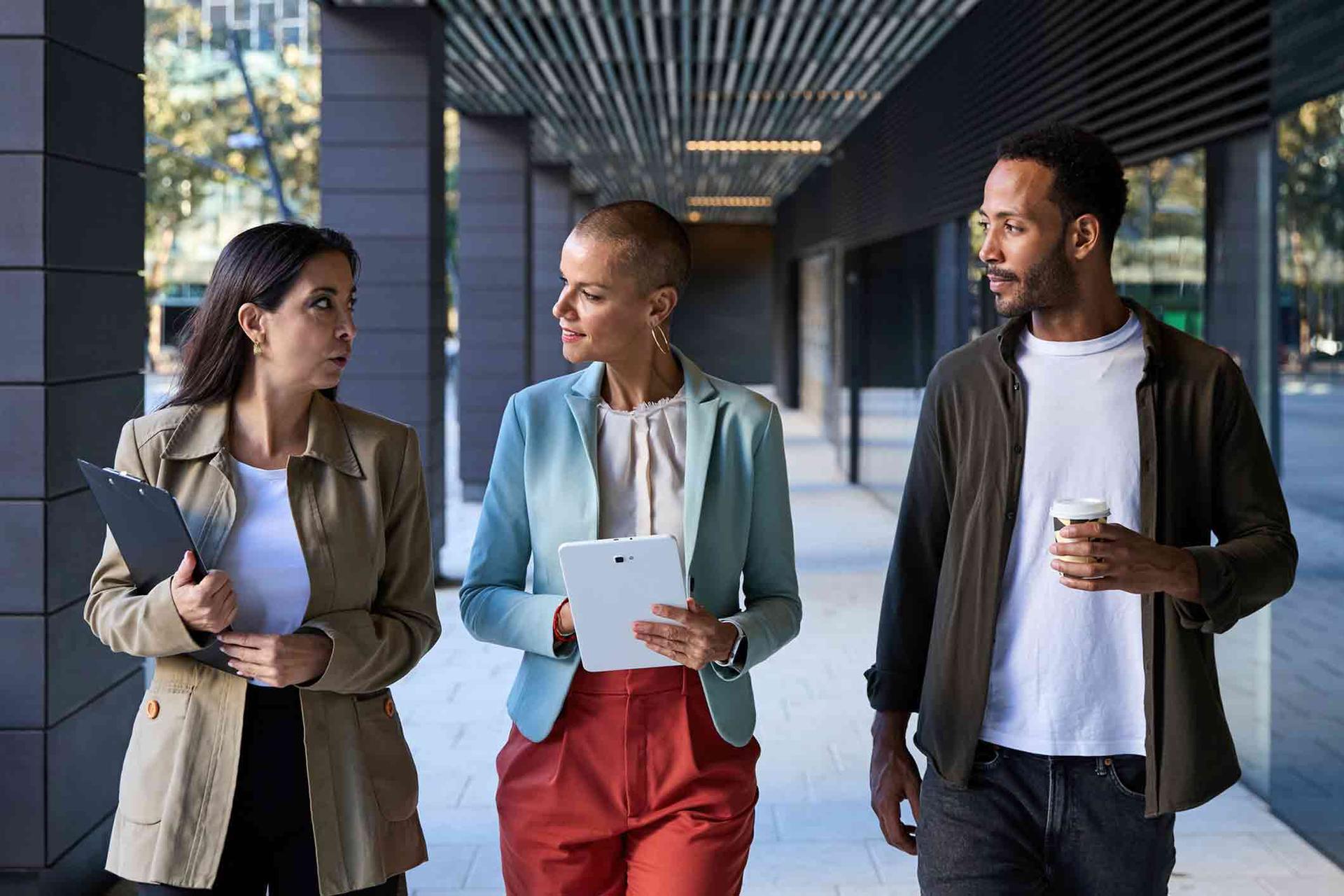 Two women and one man walking together outside their office bulding