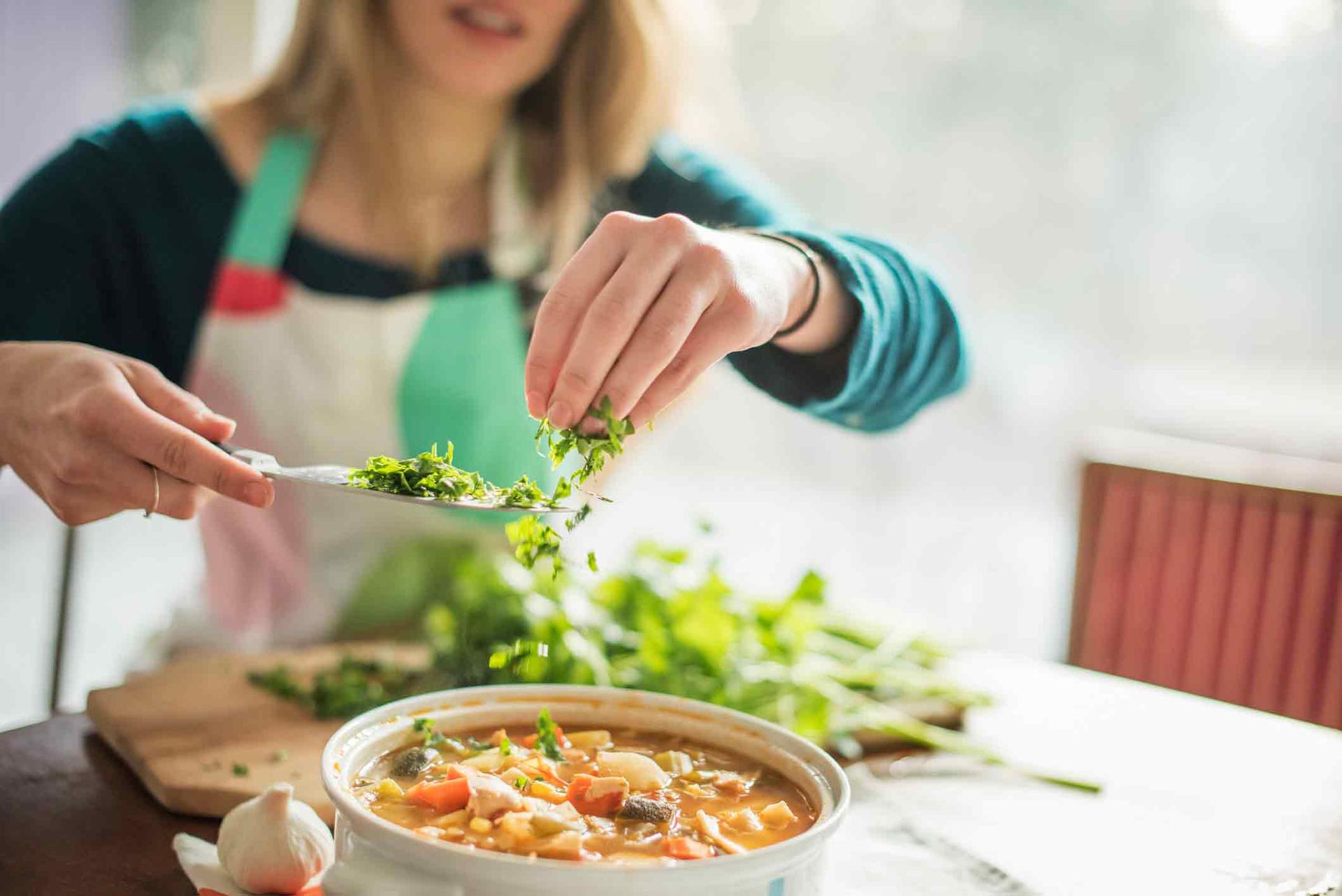 Lady making a healthy meal and adding greens