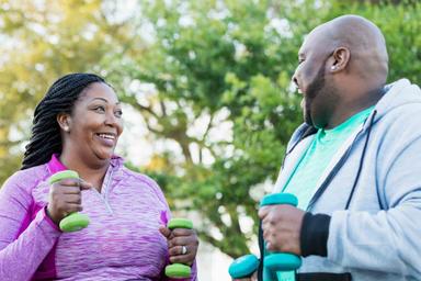 Man and woman exercising with small weights