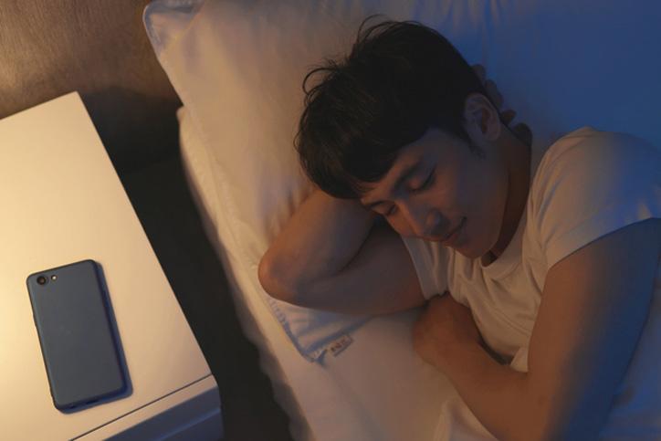 Man sleeping happily with his phone on the bedside table