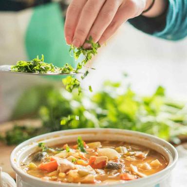 A hand adding seasoning to a stew